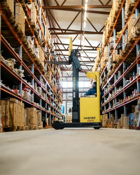 A forklift in the aisle of a large warehouse