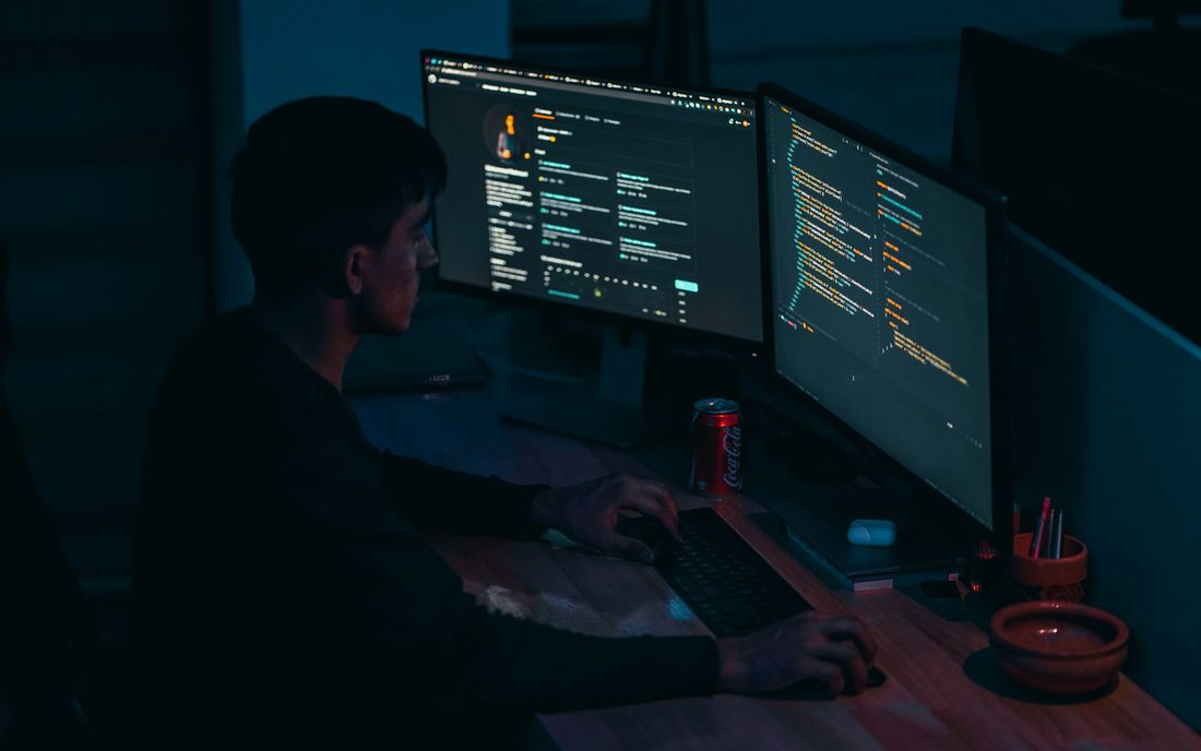 An IT professional working at a dual monitor workstation